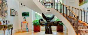 Grand stair case with unique black lacquer artwork under it with hardwood floors